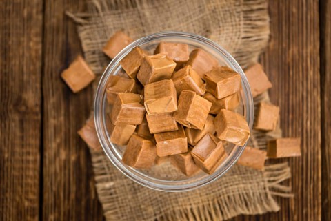 Caramel pieces as high detailed close-up shot on a vintage wooden table (selective focus)
