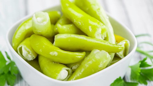 Fresh made Green Chilis (filled with cheese) on an old and rustic wooden table (selective focus,