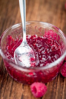 Fresh made Raspberry Jam on an old and rustic wooden table, selective focus, close-up shot