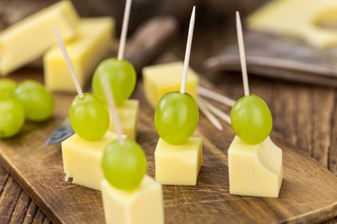Vintage wooden table with Cheese blocks and grapes as detailed close-up shot (partyfood)