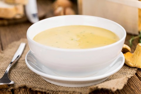 Chanterelle Soup as high detailed close-up shot on a vintage wooden table, selective focus