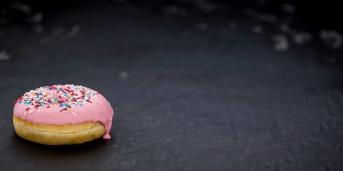 Portion of pink glazed Donuts (detailed close-up shot)