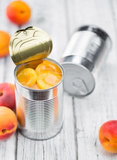 Canned Apricots on rustic wooden background (close-up shot)
