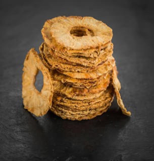 Portion of Dried Pineapple Rings on a rustic slate slab, selective focus, close-up shot