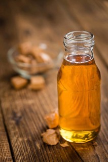 Caramel Syrup as high detailed close-up shot on a vintage wooden table (selective focus)