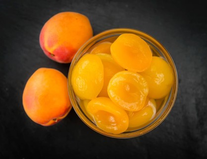 Portion of Canned Apricots as detailed close up shot on a slate slab (selective focus)