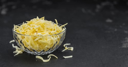 Homemade Grated Cheese (close-up shot) on a vintage slate slab