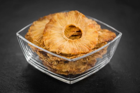 Portion of Dried Pineapple Rings on a rustic slate slab, selective focus, close-up shot
