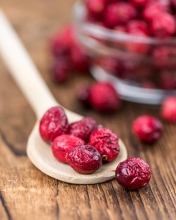 Healthy Cranberries (dried) on a wooden table as detailed close-up shot (selective focus)