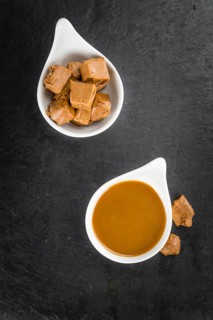 Portion of Caramel Sauce as detailed close up shot on a slate slab (selective focus)