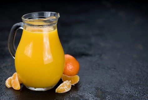 Portion of fresh made Tangerine Juice (close-up shot, selective focus)