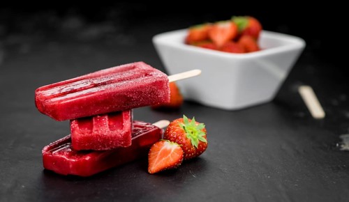 Slate slab with homemade Strawberry Popsicles (selective focus, close-up shot)
