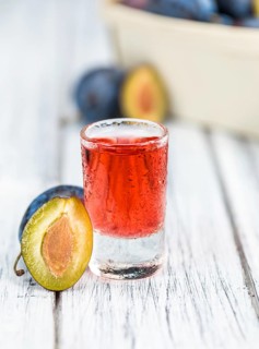 Plum Liqueur on rustic wooden background as close-up shot