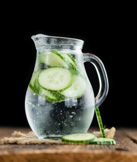 Fresh made Cucumber Water as high detailed close-up shot on a vintage wooden table, selective focus