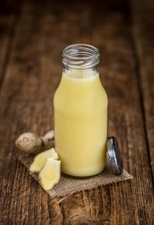 Healthy Ginger Sap on a wooden table as detailed close-up shot (selective focus)