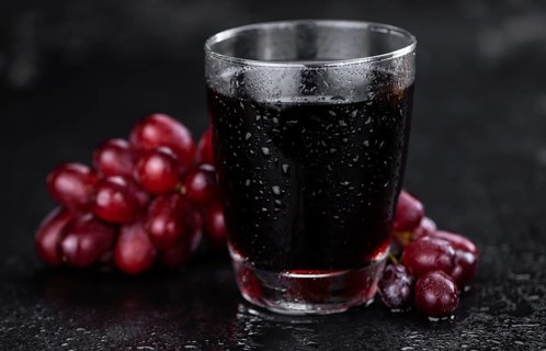 Portion of healthy Red Grape Juice on a slate slab (selective focus)