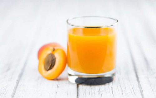 Fresh made Apricot Juice on a vintage background (close-up shot)