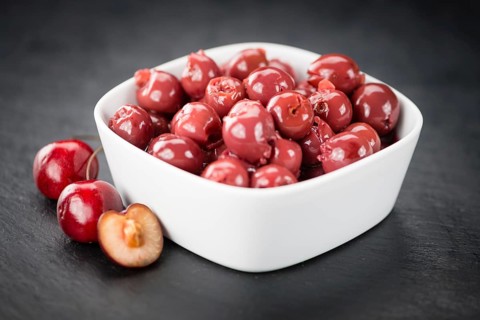 Portion of Preserved Cherries as detailed close up shot on a slate slab, selective focus