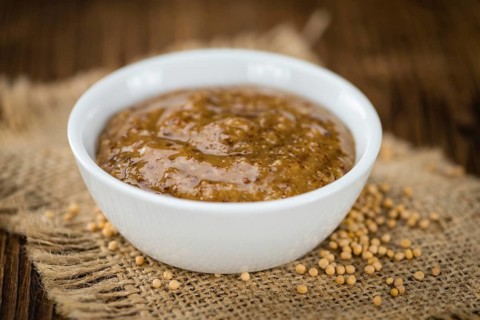 Mustard (sweet) on rustic wooden background (close-up shot)