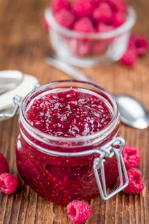 Homemade Raspberry Jam on an wooden table as detailed close-up shot, selective focus