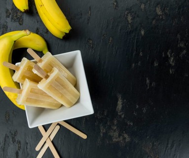 Homemade Banana Popsicles on a vintage background (close-up shot, selective focus)