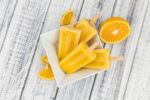 Orange Popsicles (selective focus, close-up shot) on a vintage background