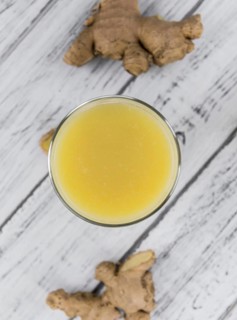 Healthy Ginger Sap on a wooden table as detailed close-up shot (selective focus)