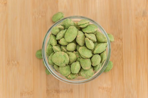 Peanuts (with Wasabi flavor) on an old wooden table as detailed close-up shot (selective focus)