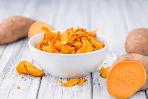 Sweet Potato Chips as high detailed close-up shot on a vintage wooden table, selective focus