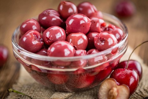 Preserved Cherries on an old wooden table as detailed close-up shot, selective focus