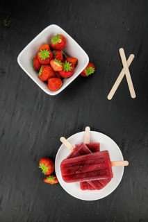 Homemade Strawberry Popsicles (close-up shot, selective focus) on vintage background