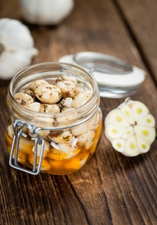 Garlic (preserved) as high detailed close-up shot on a vintage wooden table (selective focus)