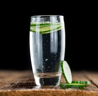 Fresh made Cucumber Water as high detailed close-up shot on a vintage wooden table, selective focus