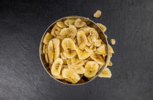 Some Dried Banana Chips on a slate slab as detailed close-up shot, selective focus
