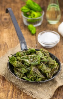 Pimientos de Padron on an old wooden table as detailed close-up shot, selective focus