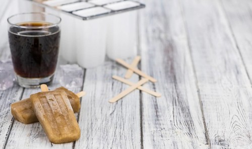 Fresh made Cola Popsicles on wooden background (selective focus, close-up shot)
