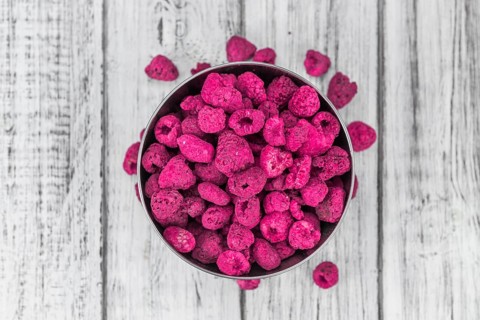 Raspberries (dried) as high detailed close-up shot on a vintage wooden table, selective focus