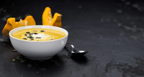 Portion of fresh made Pumpkin Soup (close-up shot) on rustic background