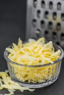 Homemade Grated Cheese (close-up shot) on a vintage slate slab