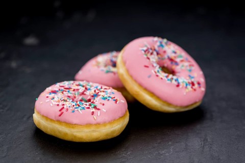 Portion of pink glazed Donuts (detailed close-up shot)