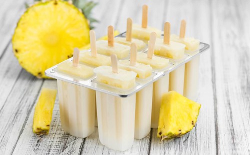 Old and rustic wooden table with homemade Pineapple Pipsicles (selective focus, close-up shot)