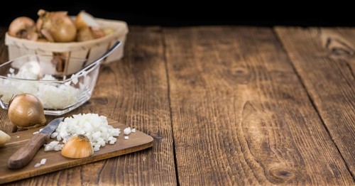 White Onions (dices) as high detailed close-up shot on a vintage wooden table, selective focus