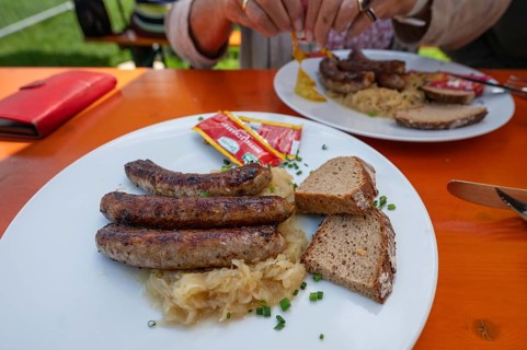 Three Franconian bratwursts with mustard and bread served in a garden withe, Bavaria, Germany,