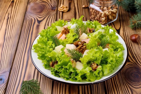 A fresh salad on a wooden table with nuts and fir branches. Healthy and natural meal, AI generated,