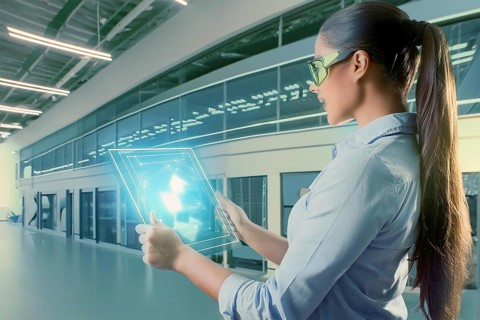 Woman in modern laboratory setup with tablet, surrounded by holographic representations and