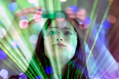 A woman in safety goggles works intently with green light and laser effects, AI and illustration