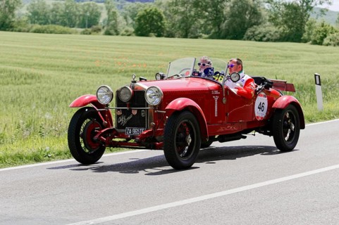Red classic car with driver and co-driver on a country road during a rally, classic car, car race,