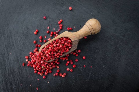 Portion of Pink Peppercorns as detailed close up shot on a slate slab, selective focus