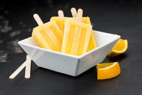 Orange Popsicles (selective focus, close-up shot) on a vintage background