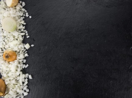 Some White Onions (dices) on a slate slab as detailed close-up shot, selective focus